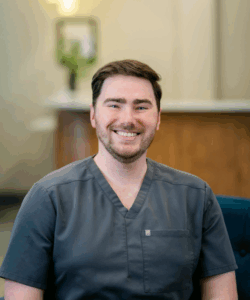Dr. Patrick Wilson, dentist at Progressive Dental Care, smiling in professional attire, showcasing a welcoming atmosphere in a dental office setting.