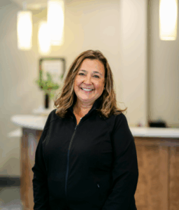 Dental team member smiling in front of reception area at Progressive Dental Care, showcasing a welcoming environment for patients.