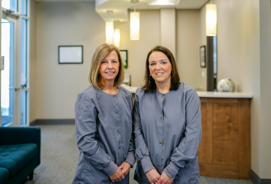 Dental assistants at Progressive Dental Care smiling in professional attire, standing in a welcoming dental office environment with modern decor.